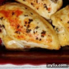 A close up photo of golden roasted chicken breasts in a red roasting pan, part of the recipe card.