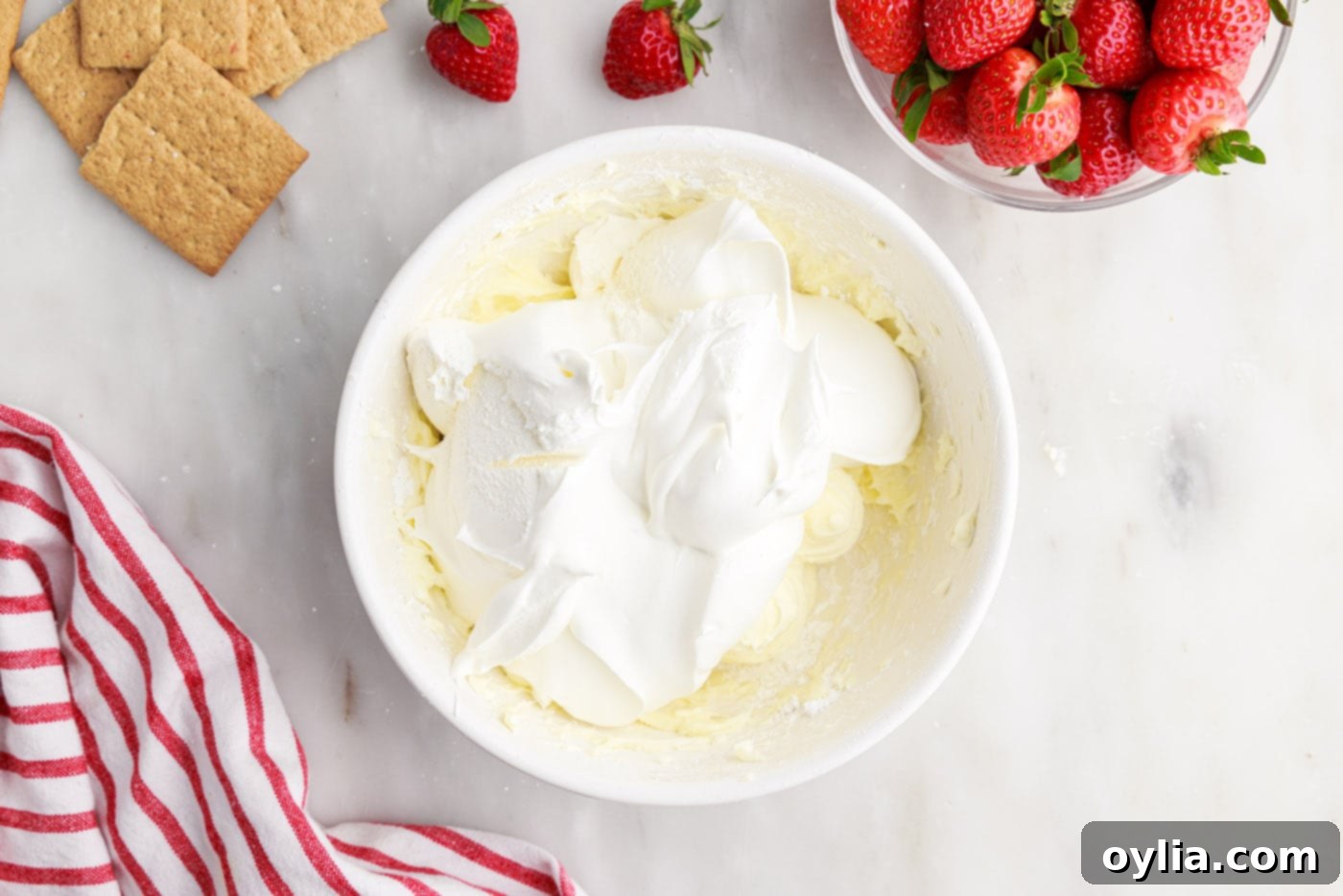 cool whip on top of cheesecake mixture in a bowl