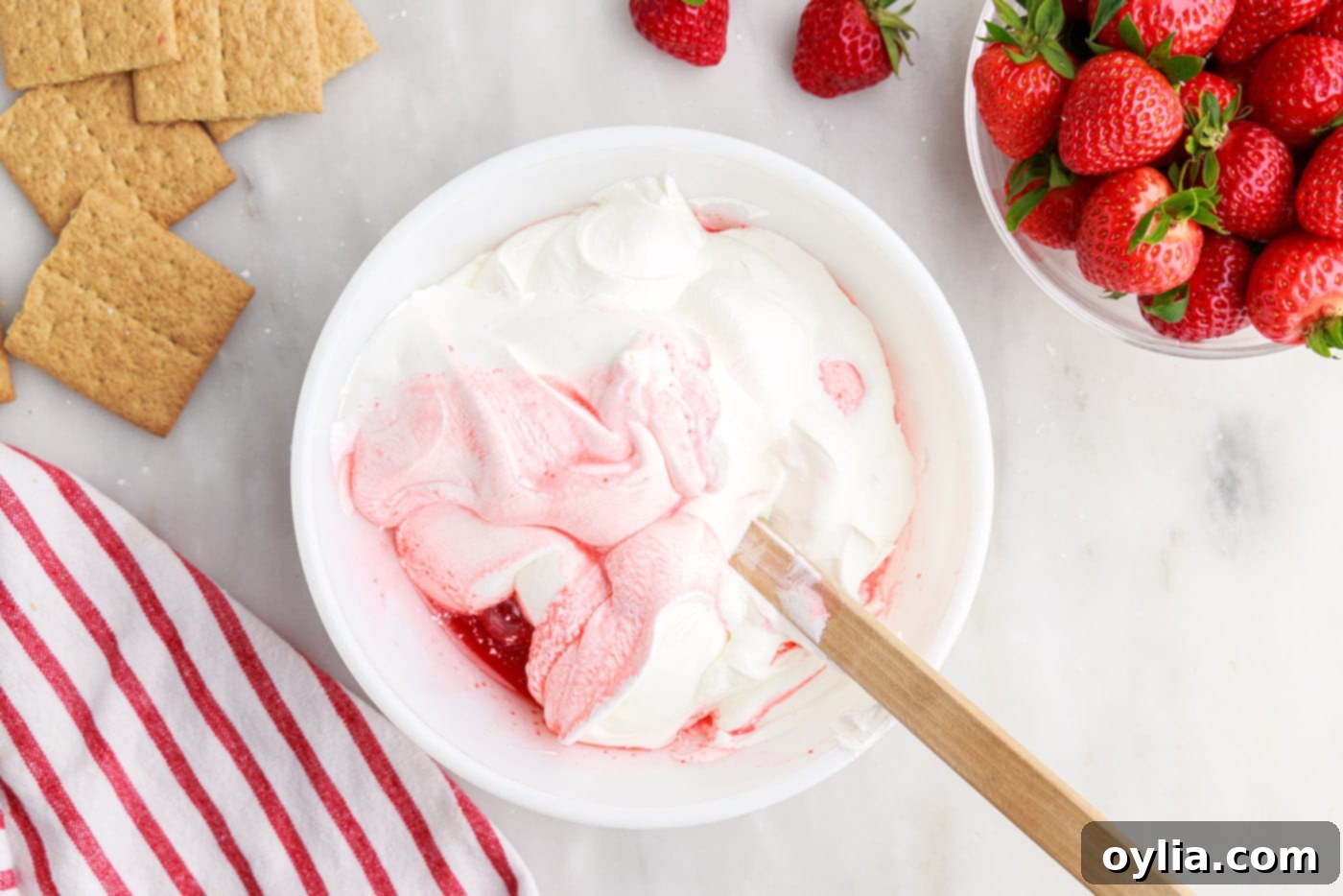 wooden spoon folding whipped topping into strawberry mixture