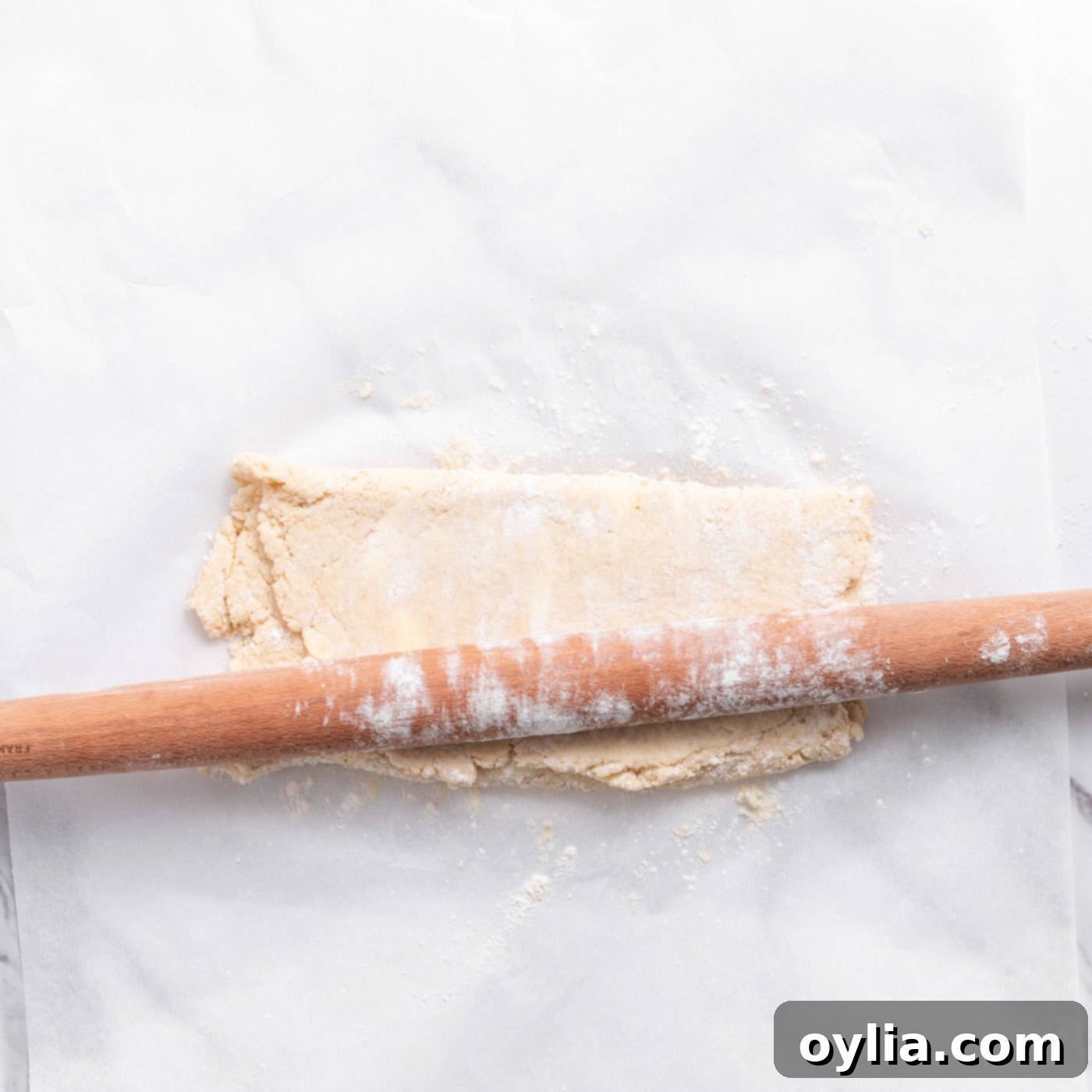 floured rolling pin pressing biscuit dough