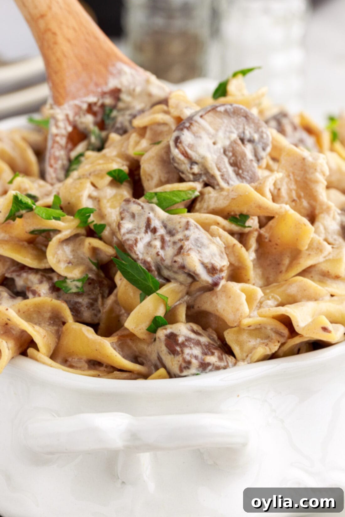 wooden spoon lifting out Instant Pot Beef Stroganoff with creamy sauce