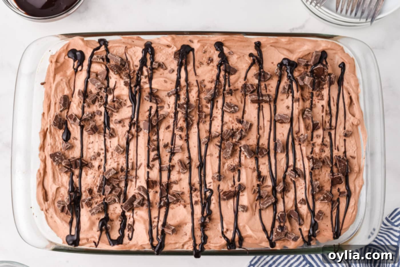 finished Triple Chocolate Poke Cake with chocolate whipped cream, chopped chocolate, and chocolate drizzle