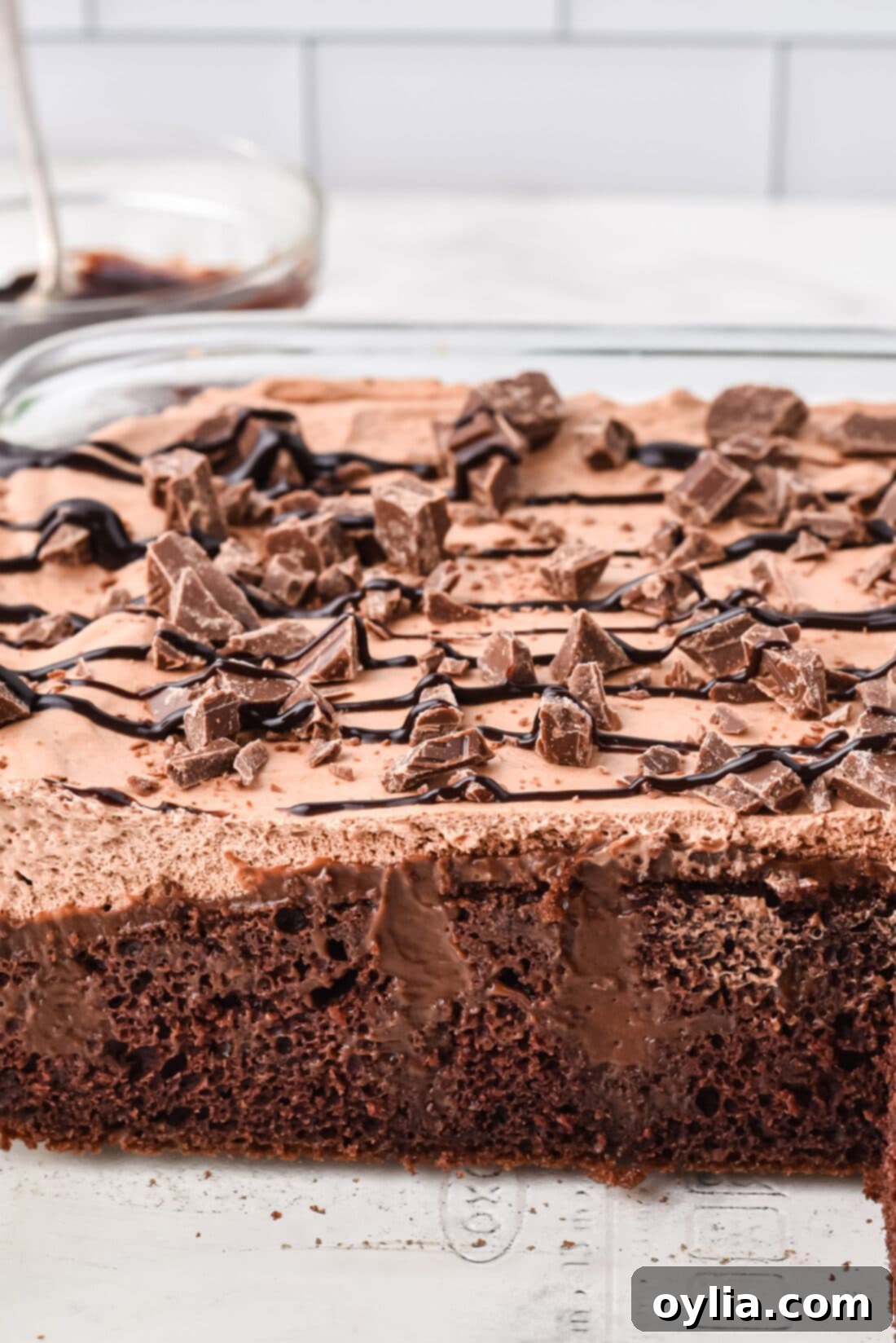 Decadent Chocolate Poke Cake 3 full pan of Triple Chocolate Poke Cake, showcasing the rich chocolate layers, fluffy whipped topping, and garnished with chocolate shavings and chocolate syrup.