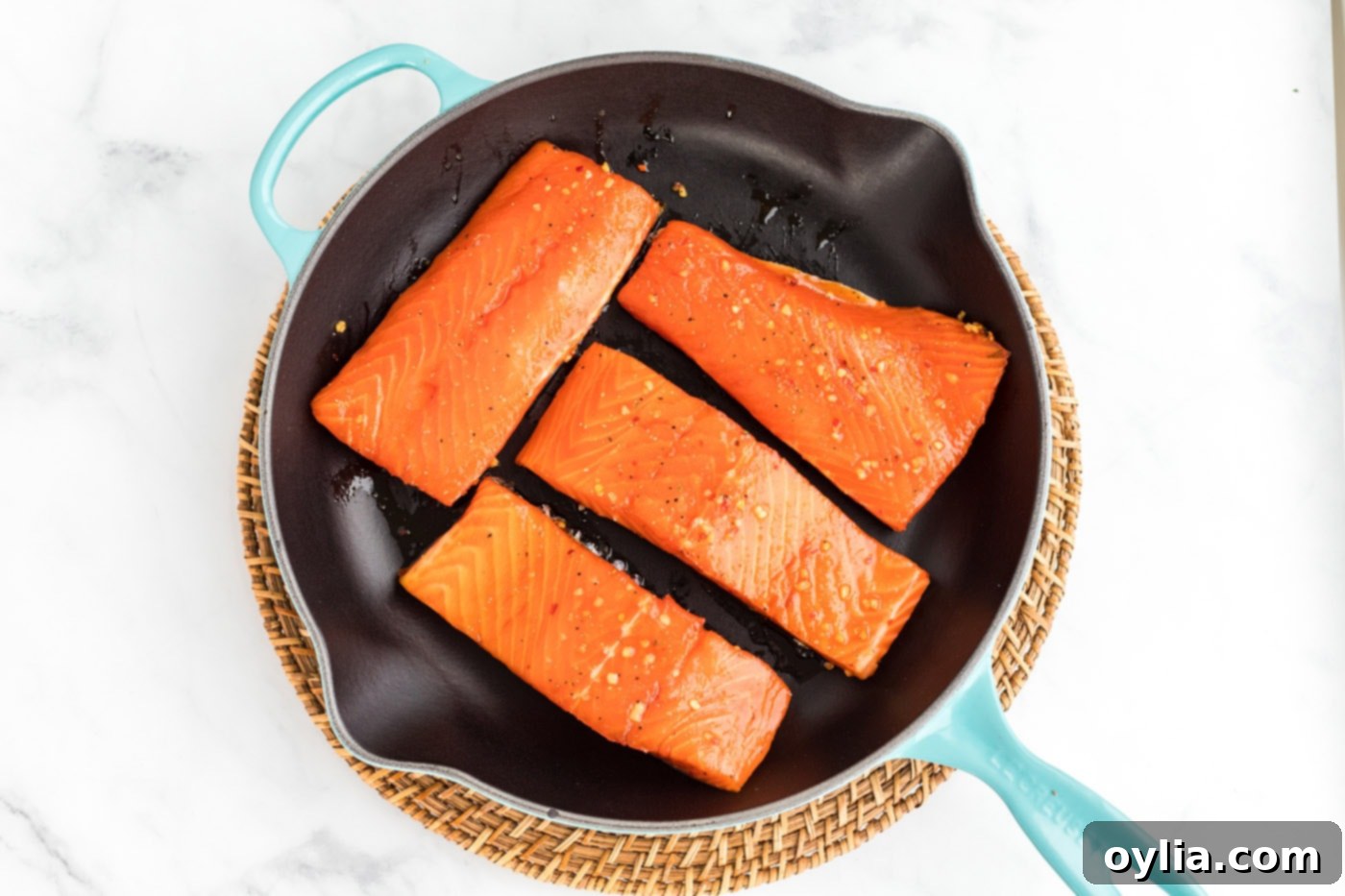 Salmon filets in a skillet, brushed with marinade