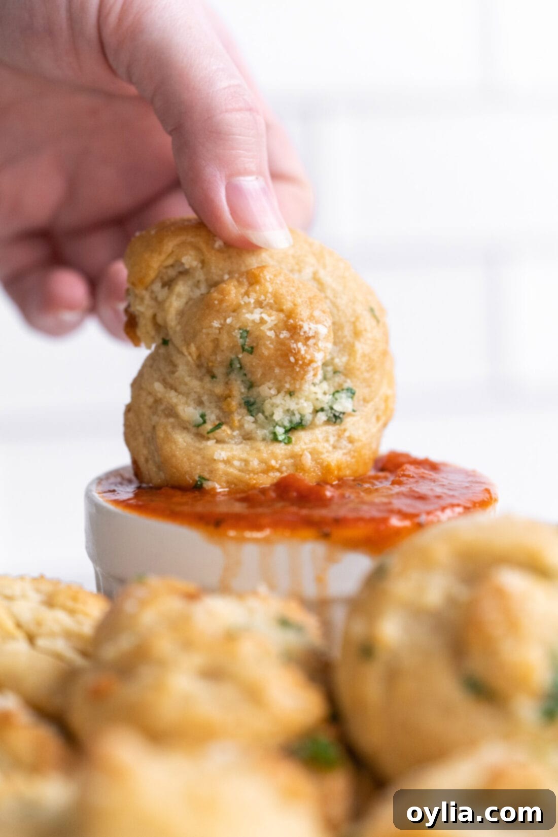 dipping a golden garlic knot into marinara sauce