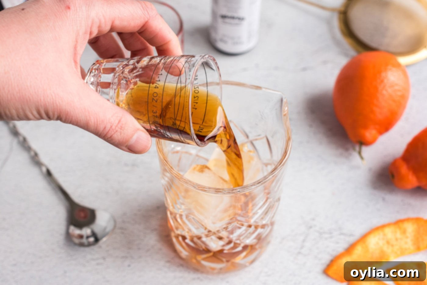 Pouring whiskey and vermouth into a mixing glass filled with ice
