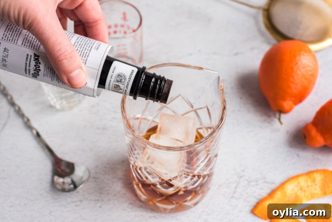 Adding dashes of bitters to the Manhattan cocktail in the mixing glass