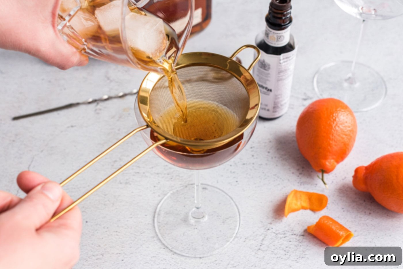 Straining a Manhattan cocktail into a coupe glass, ready for garnish