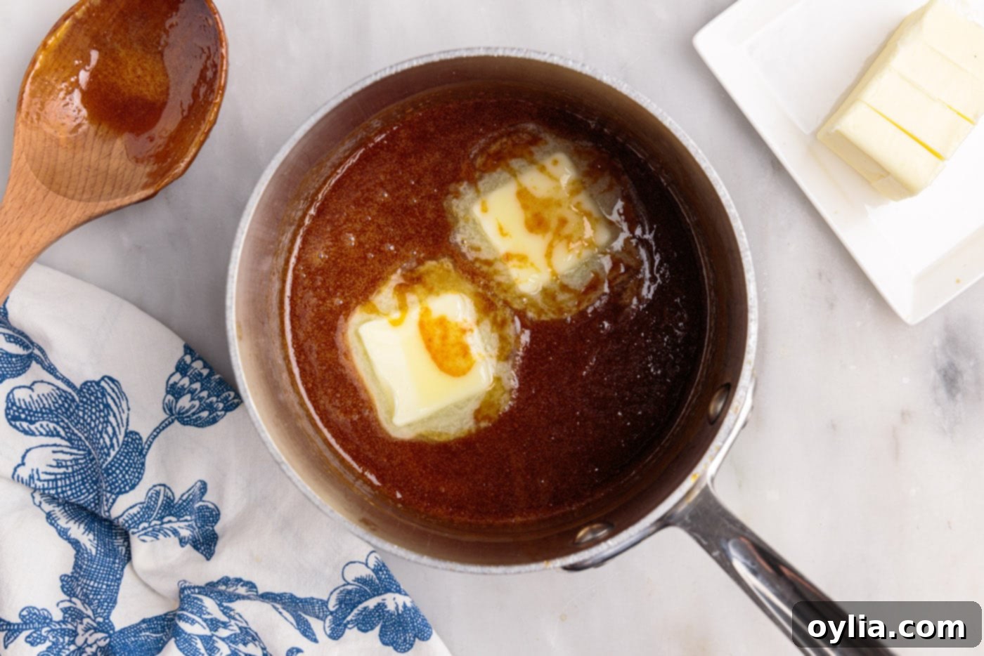 Adding cut pieces of unsalted butter to the still-warm caramel sauce.
