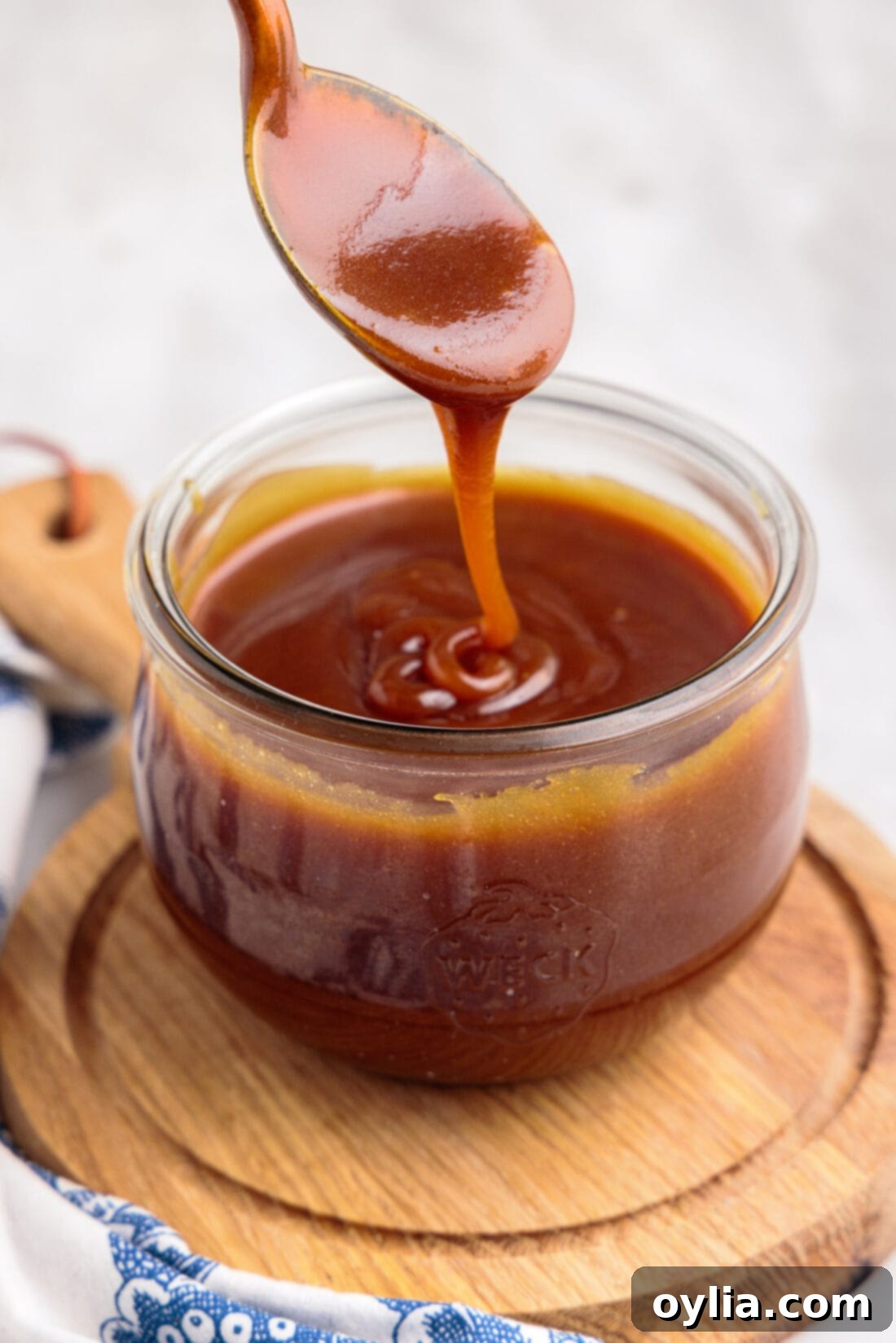 A spoon resting in a jar of freshly made, golden homemade caramel sauce, ready to be enjoyed.