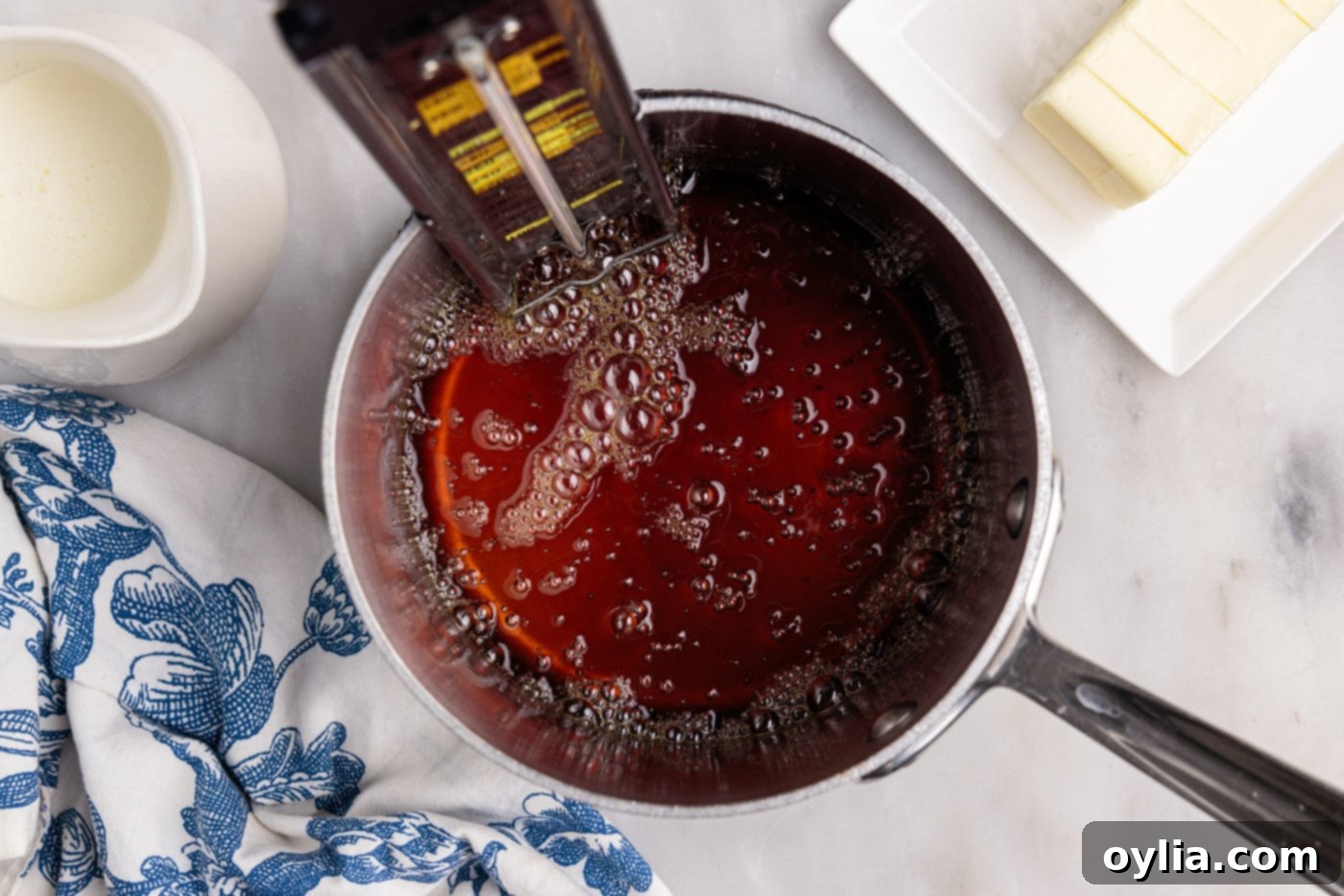 Amber colored caramel sauce simmering and bubbling in a saucepan, indicating it's reached the desired caramelization stage.