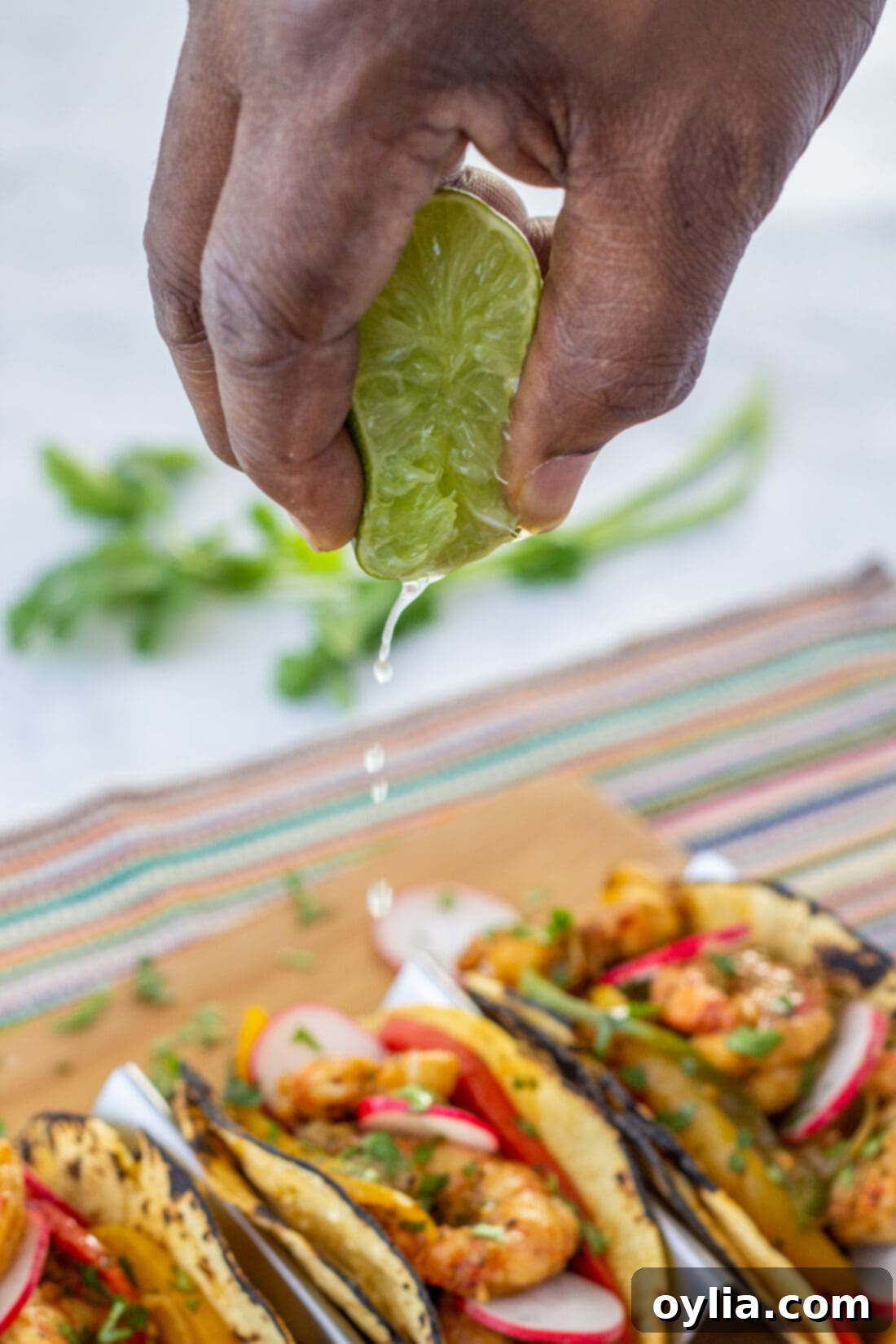 Fresh lime being squeezed over a plate of hot shrimp fajitas for extra zest
