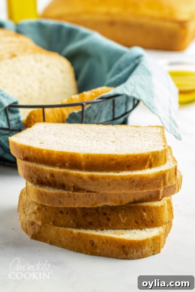 Multiple slices of fresh homemade white bread neatly stacked on a wooden board.