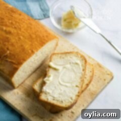 A close-up of a slice of homemade white bread with melted butter, ready to be enjoyed.