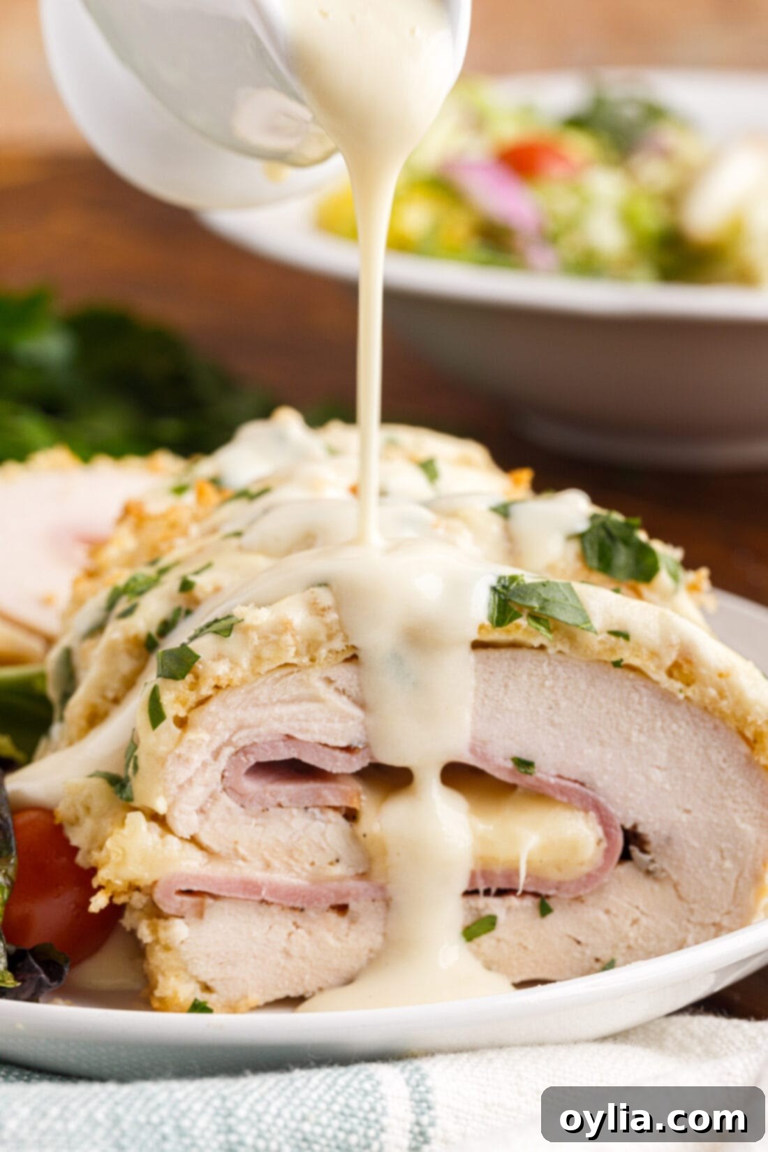 drizzling sauce on Chicken Cordon Bleu