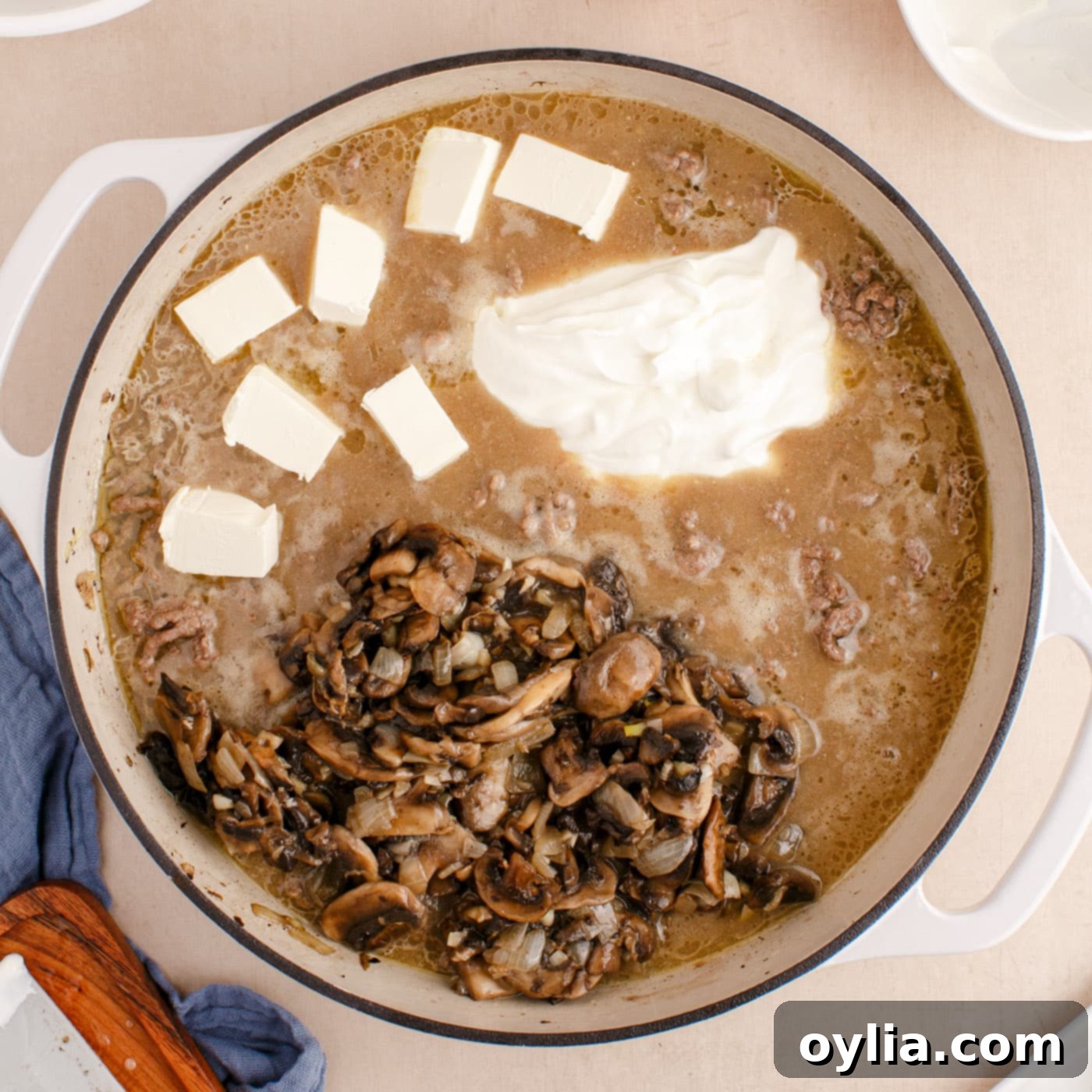 mushrooms, sour cream, and cream cheese added to ground beef stroganoff in a skillet