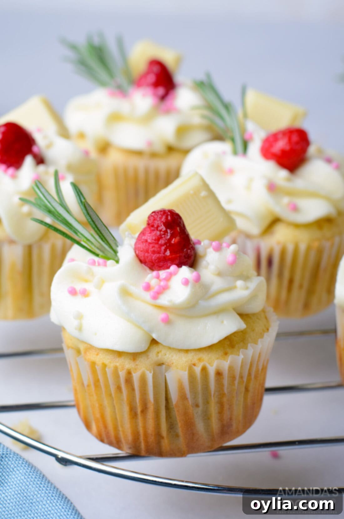 Raspberry White Chocolate Cupcakes on a rack, perfectly frosted and garnished