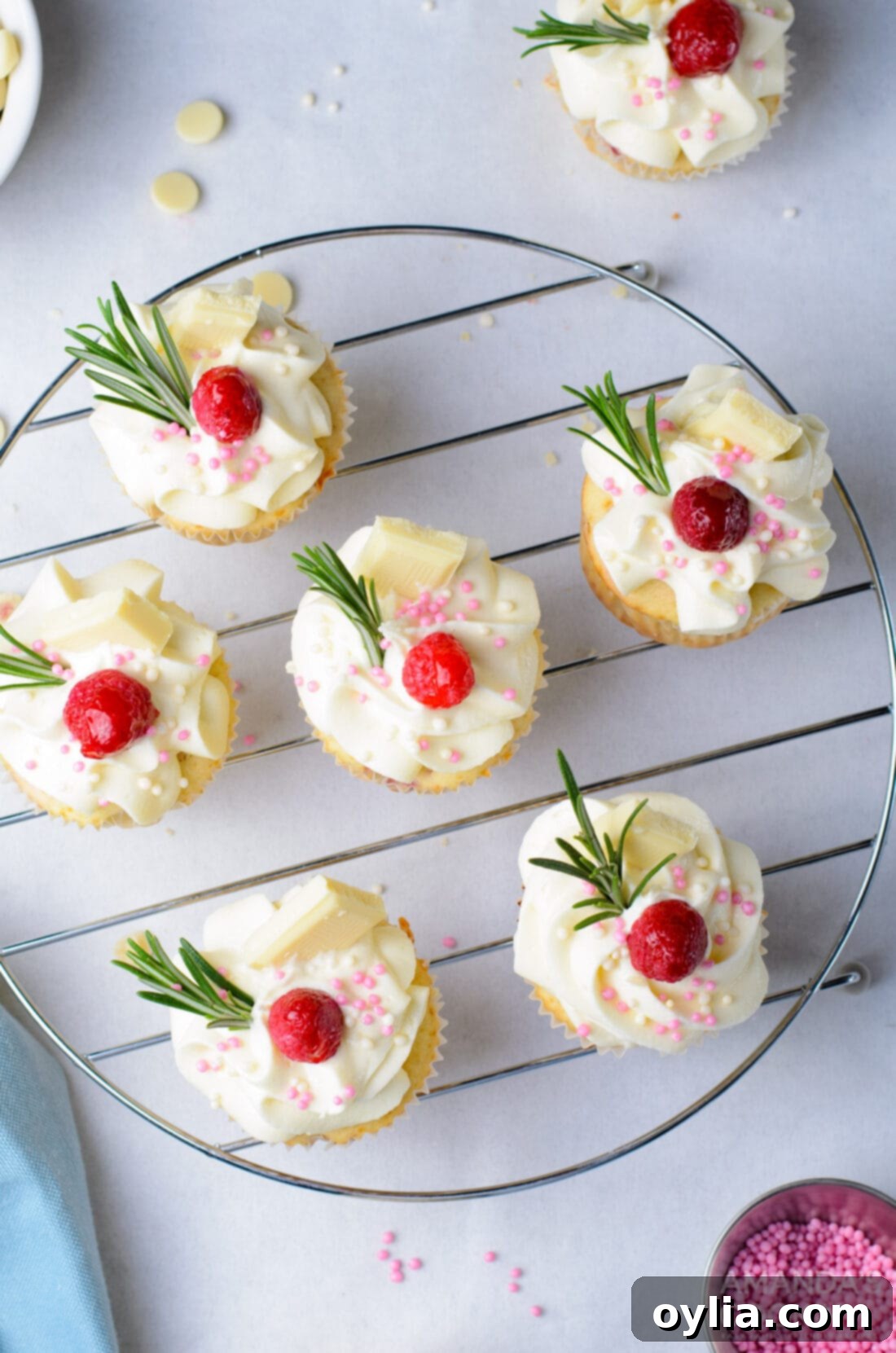 overhead photo of Raspberry White Chocolate Cupcakes on a rack with garnishes