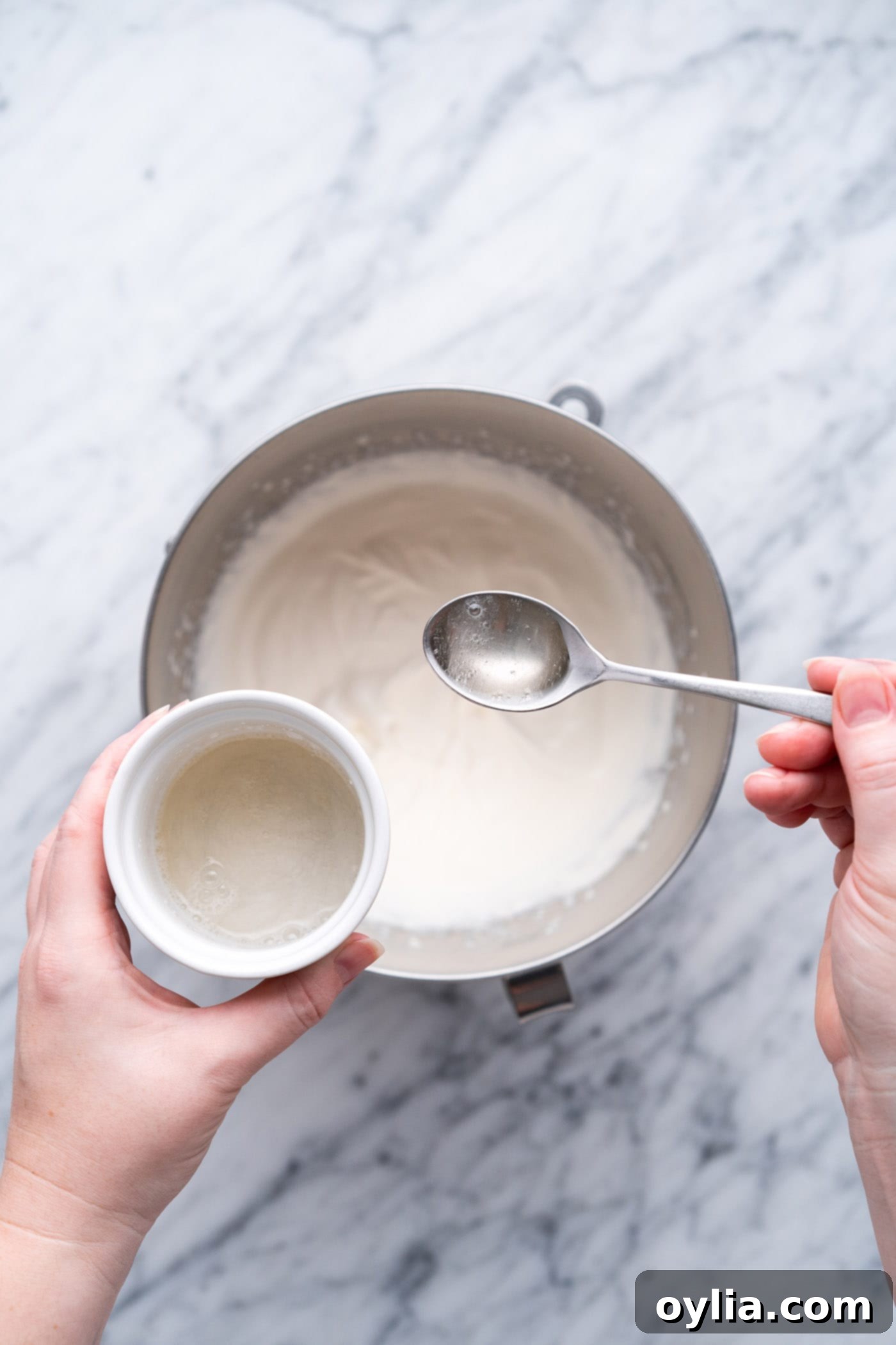 Slowly adding dissolved gelatin to whipped cream while the mixer is running on low speed