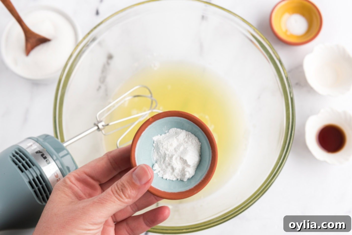 adding cream of tartar to egg whites in a bowl for whisking