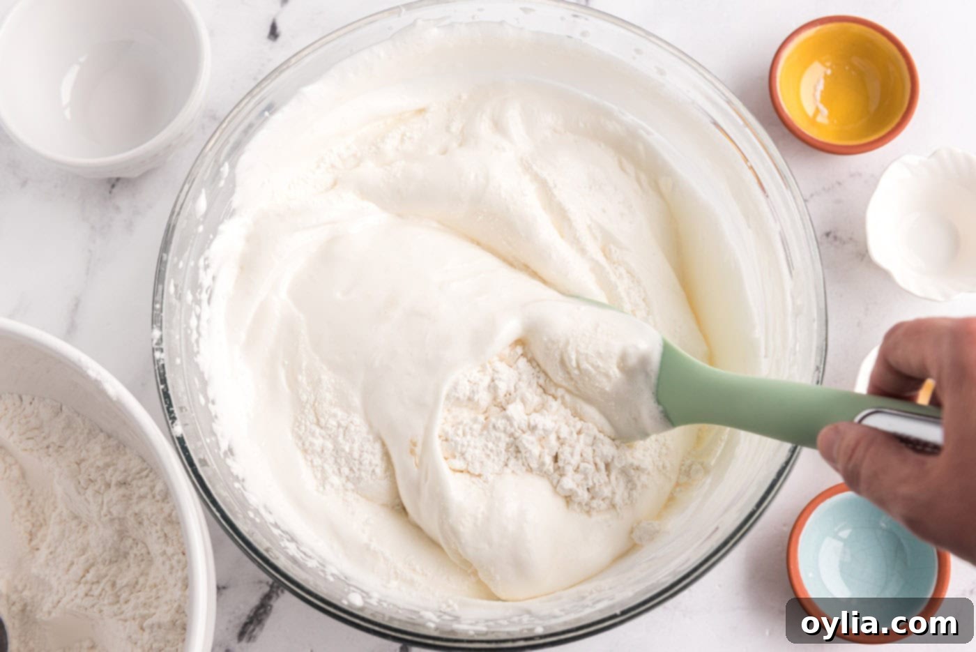 folding flour mixture into egg white mixture in a bowl with a rubber spatula