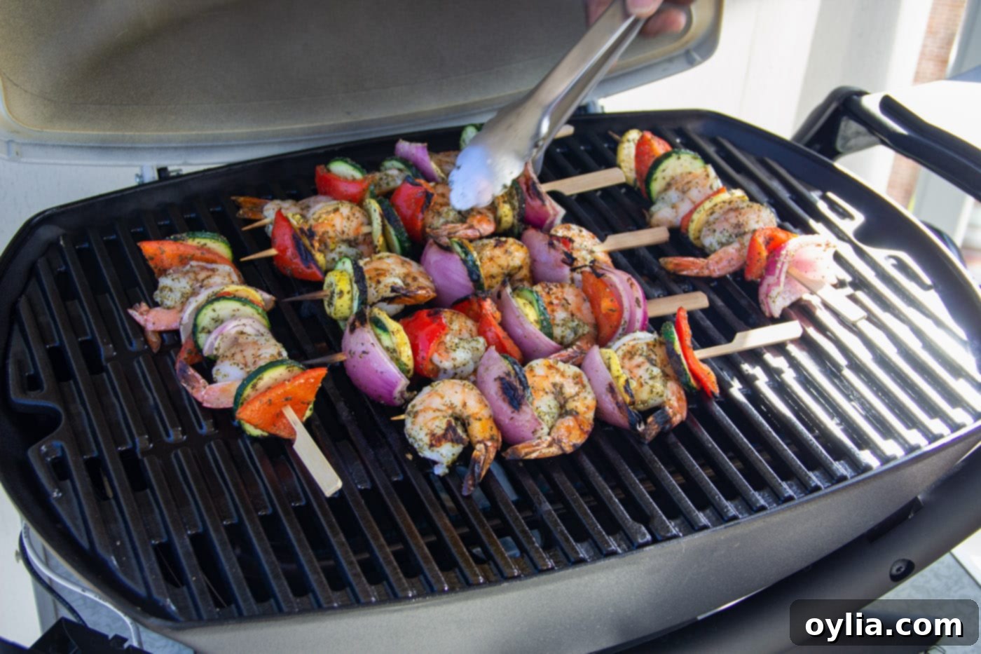 Shrimp kabobs sizzling on the hot grill with the lid open.