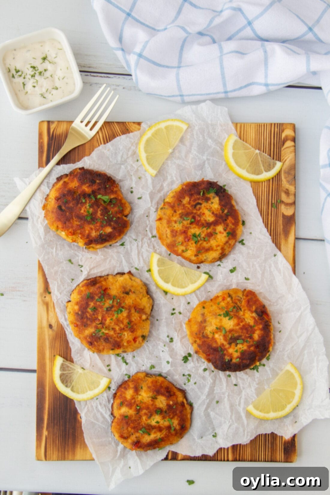Crispy golden smoked salmon fish cakes arranged on a wooden cutting board, garnished with fresh herbs.