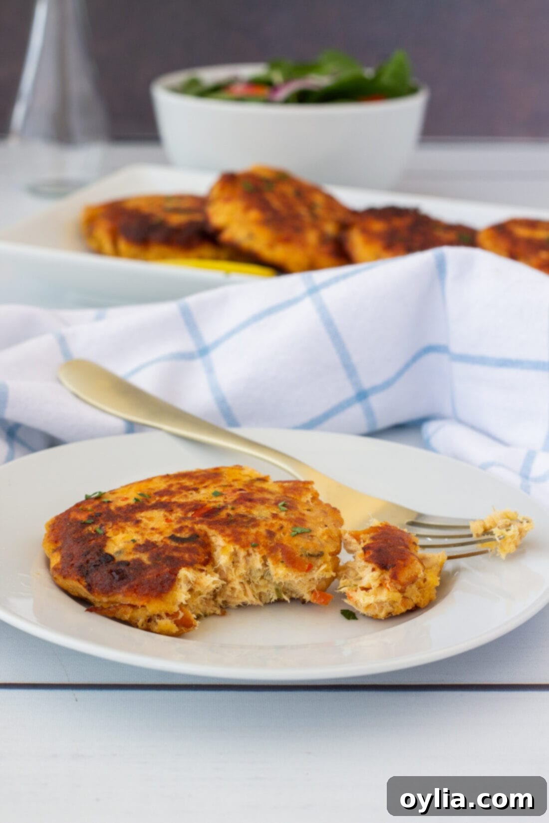 A single smoked salmon fish cake with a portion removed by a fork, showing the tender, flaky interior.