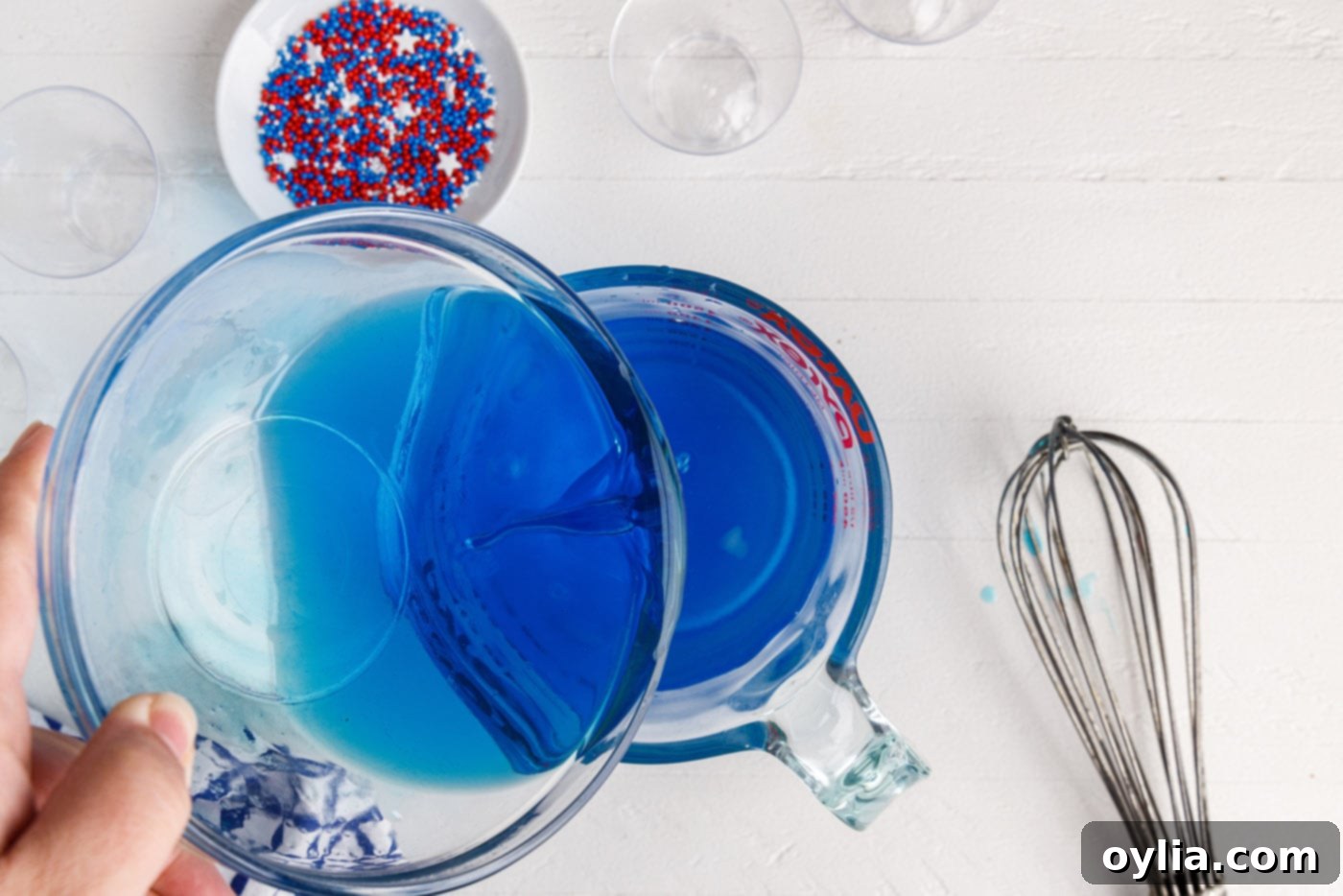 Pouring vodka into a measuring cup with blue jello mixture