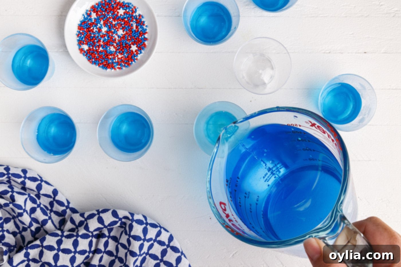 Pouring blue jello mixture into plastic shot glasses for the first layer
