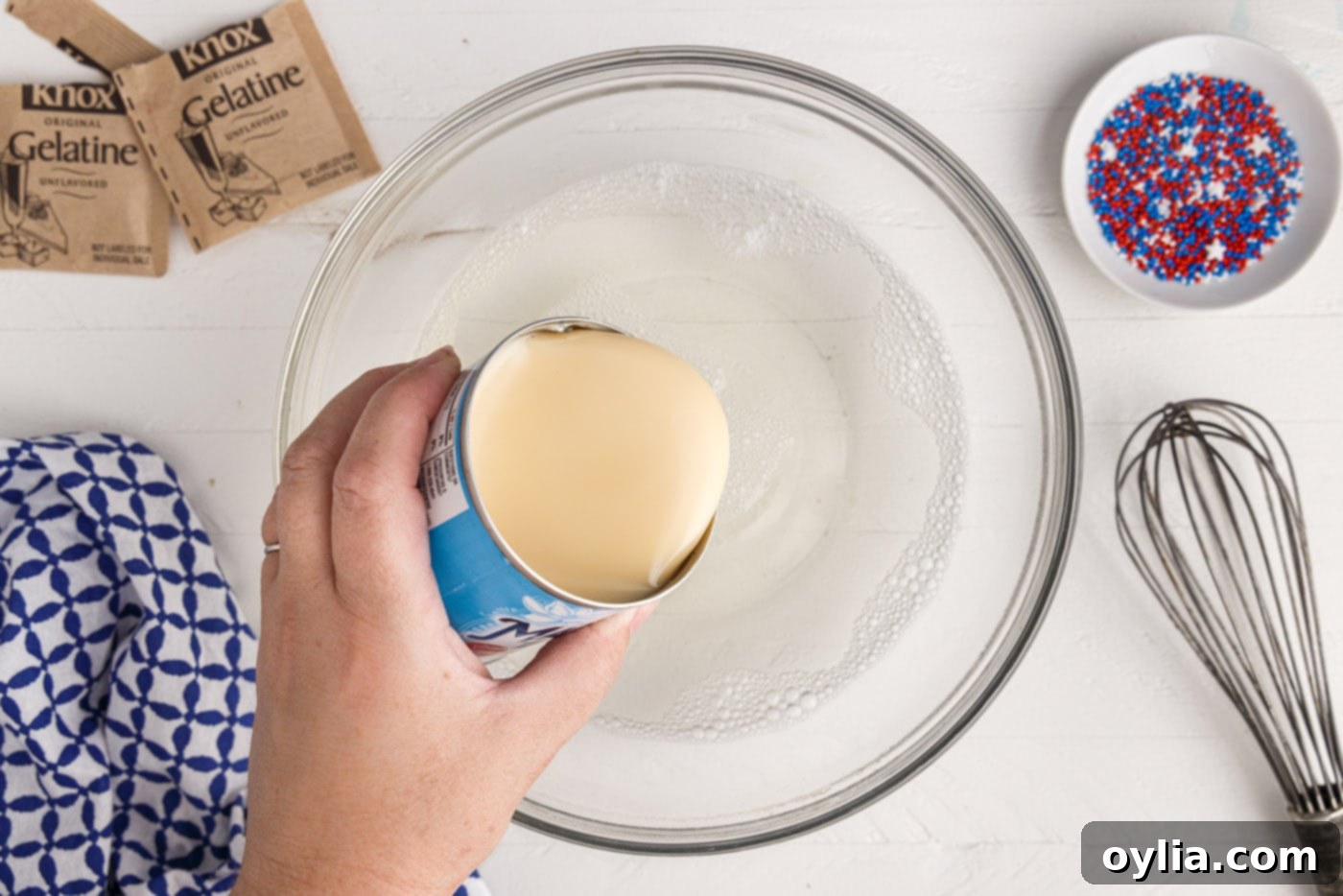 Adding sweetened condensed milk to dissolved gelatin for the white jello layer