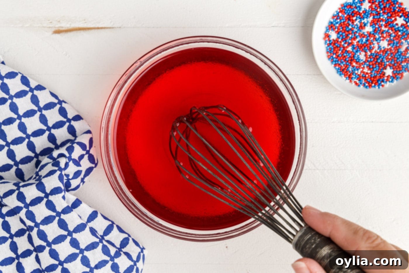 Whisking red jello powder with boiling water to prepare the red layer