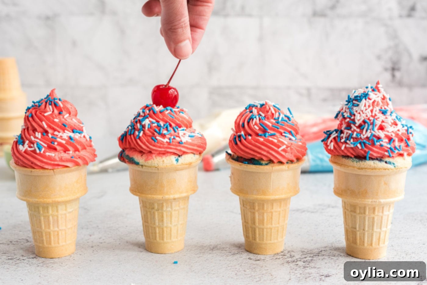 adding maraschino cherry to ice cream cone cupcakes as a final garnish