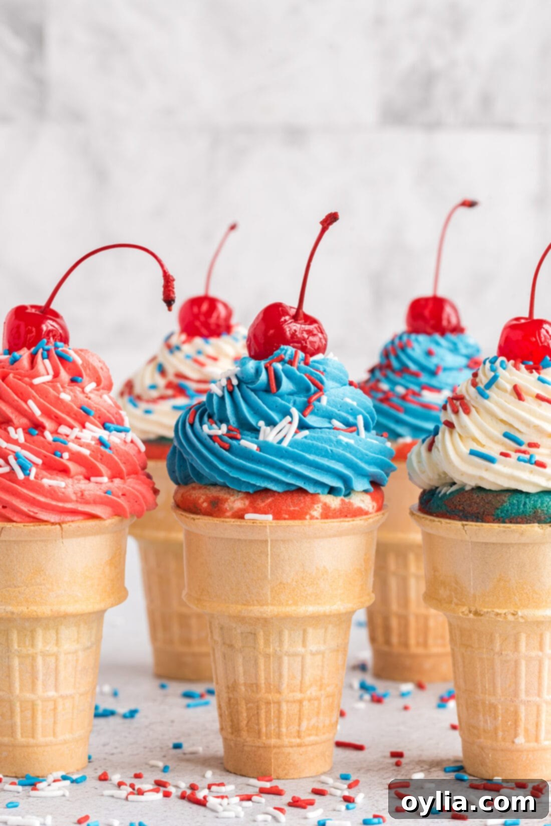 Patriotic Ice Cream Cone Cupcakes topped with cherries and sprinkles