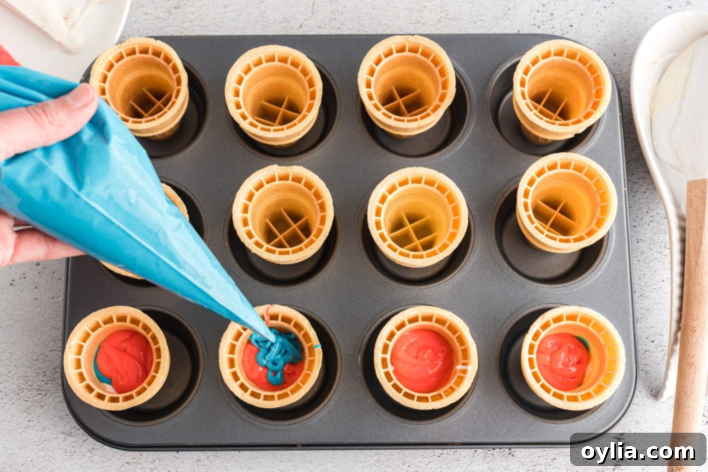 piping blue cake batter inside an ice cream cone as the third layer