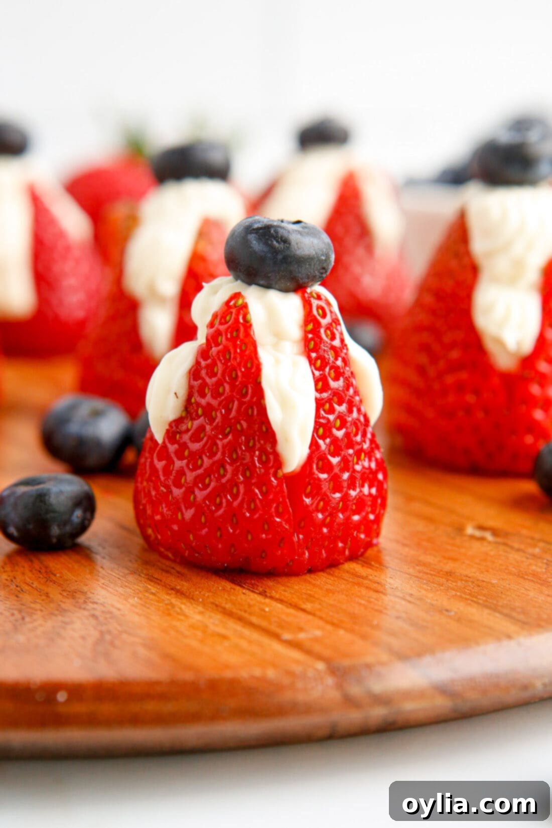 Cheesecake Stuffed Strawberries with a blueberry on top, garnished beautifully on a plate.
