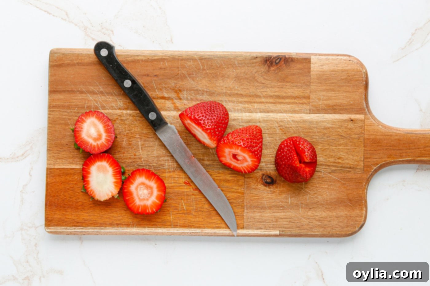 Slicing the top off of strawberries for cheesecake stuffing.