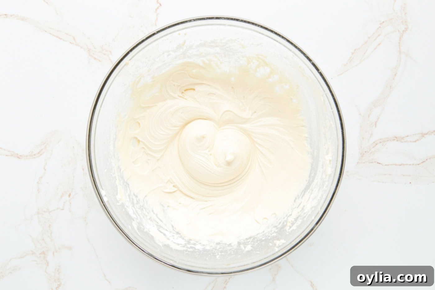 Cream cheese being beaten in a bowl until smooth.