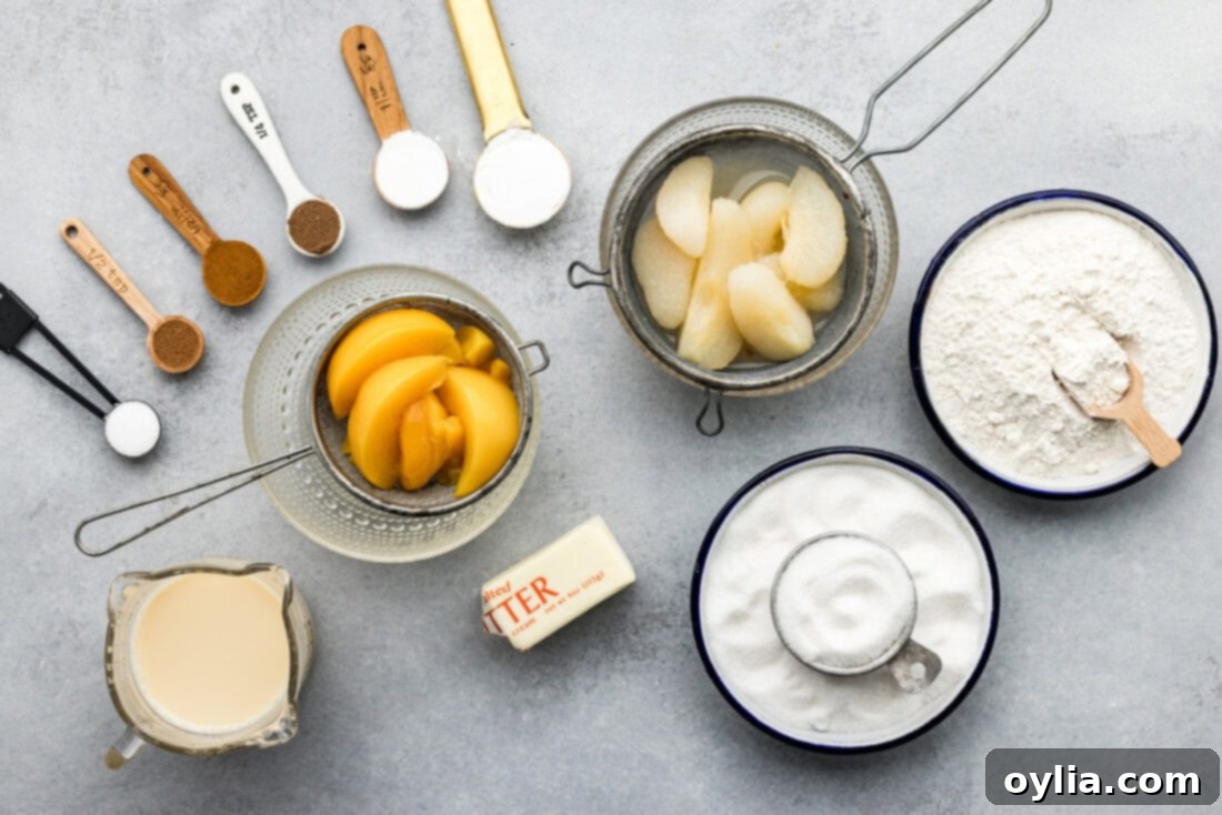 A flat lay photograph showing all the ingredients required for Pear-Peach Cobbler, including canned peaches and pears, butter, sugars, flour, spices, and evaporated milk.