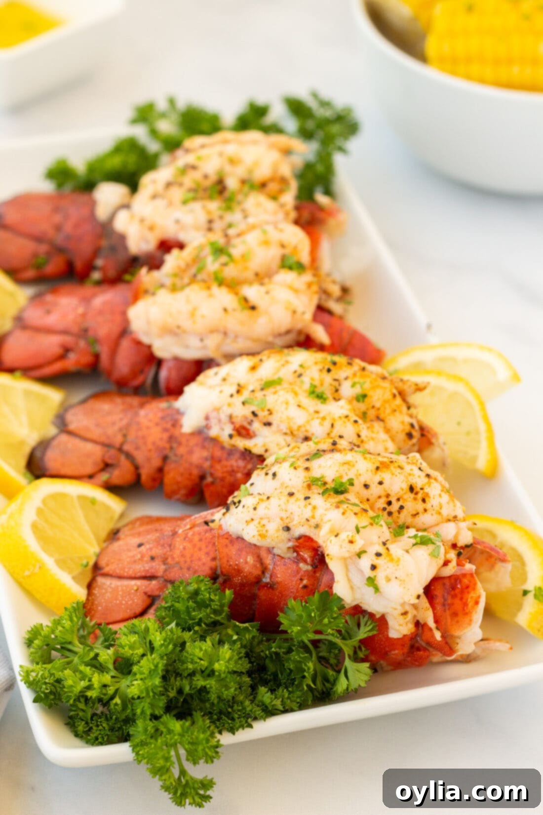 Tender Steamed Lobster Tail 19 Four perfectly steamed lobster tails arranged on a platter with lemon and herbs