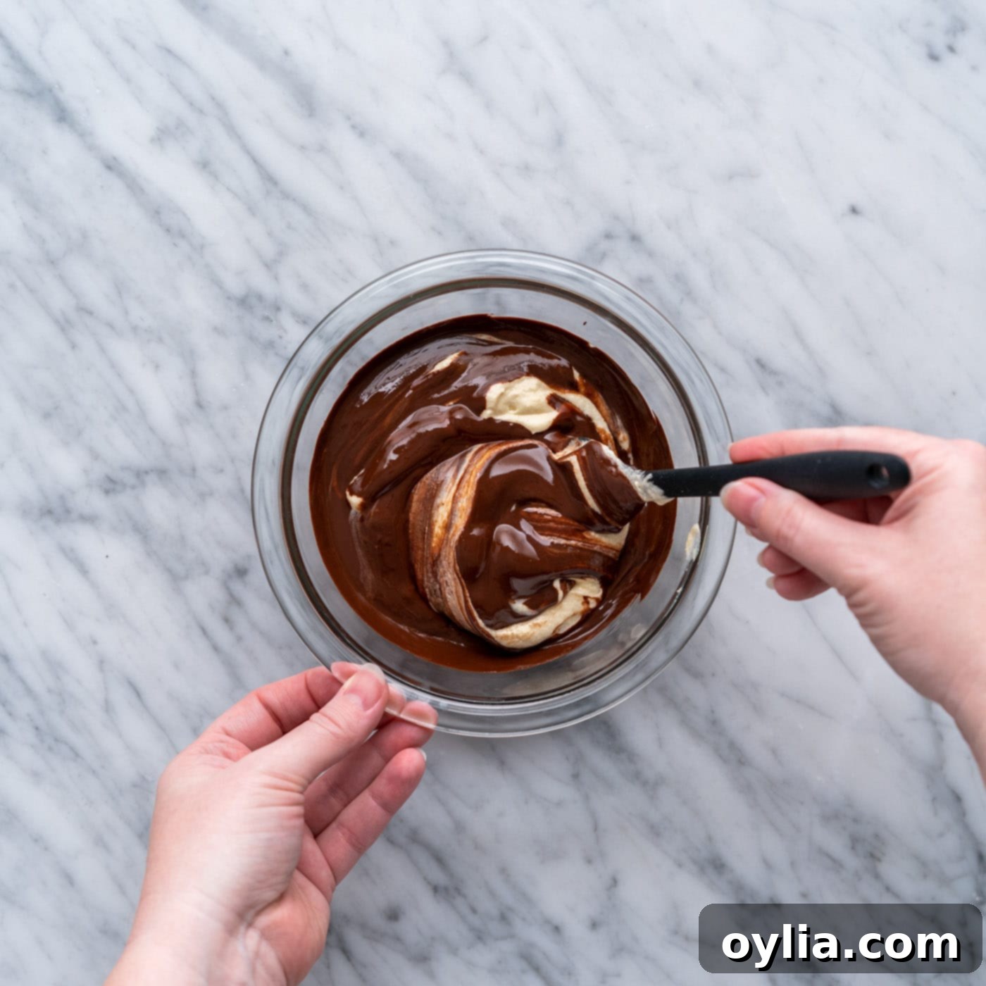 Melted chocolate being stirred into a cup of yellow cake batter to create chocolate batter