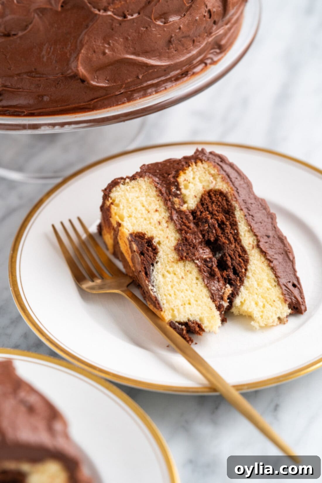A slice of Marble Cake on a plate with a fork, showcasing the fluffy texture and perfect swirls of chocolate and vanilla