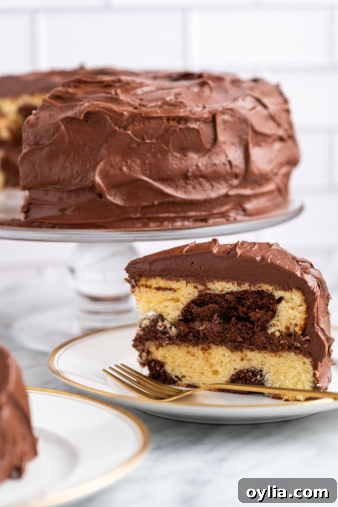 slice of Marble Cake on a white plate with a fork, showing distinct swirls of chocolate and yellow cake