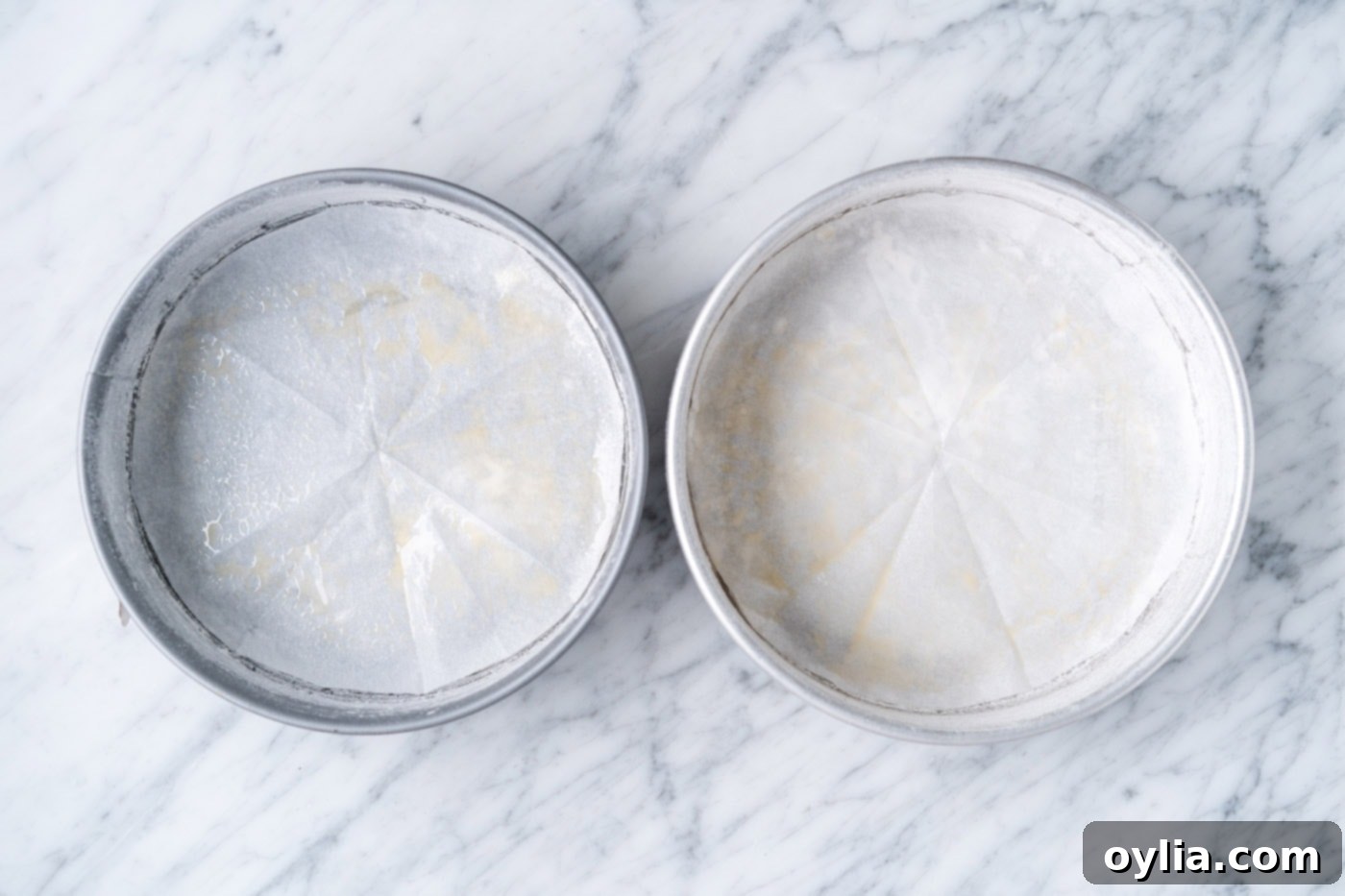 Two 9-inch round cake pans prepared with butter, flour, and parchment paper lining the bottom