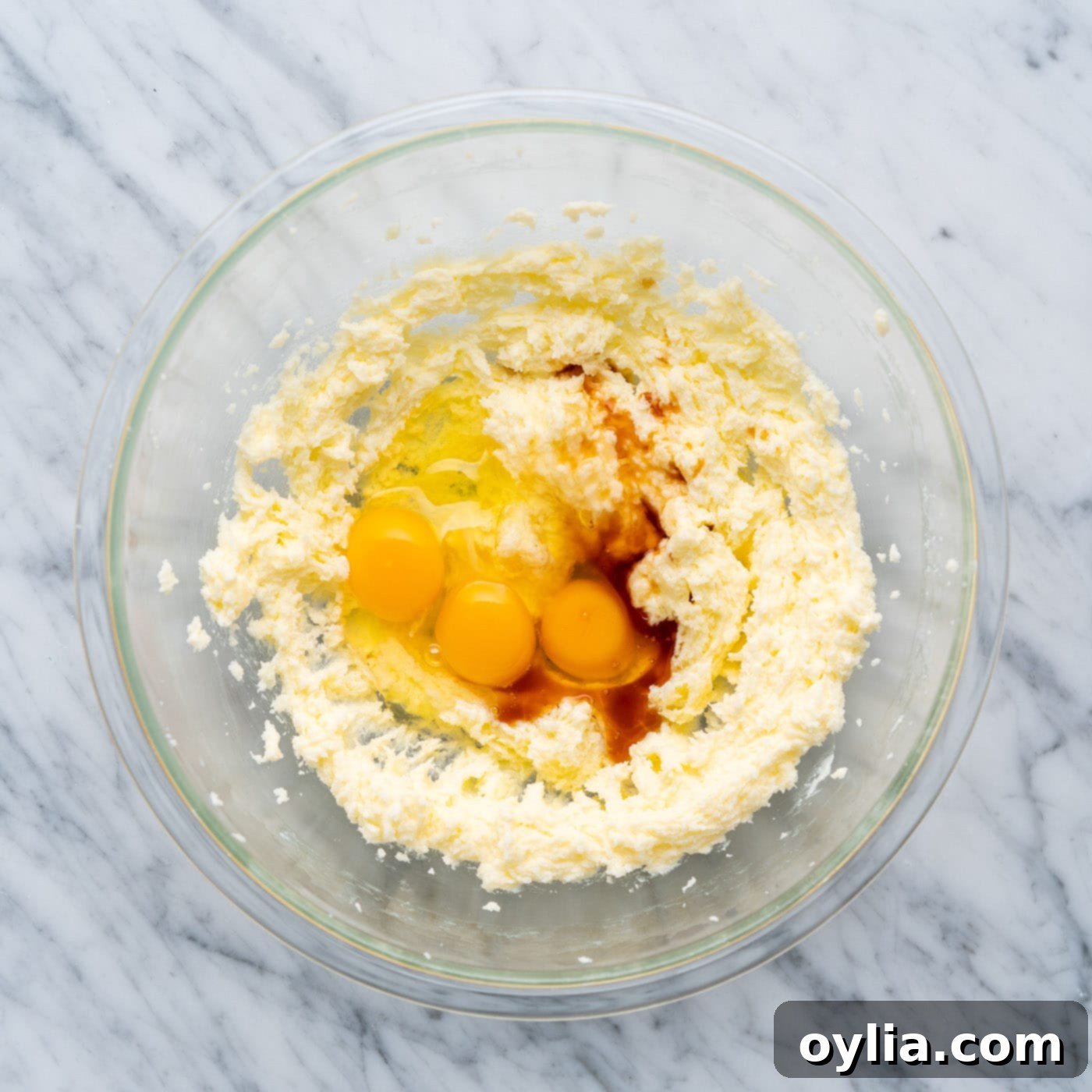 Eggs and vanilla extract being added to the creamed butter and sugar mixture in a large bowl