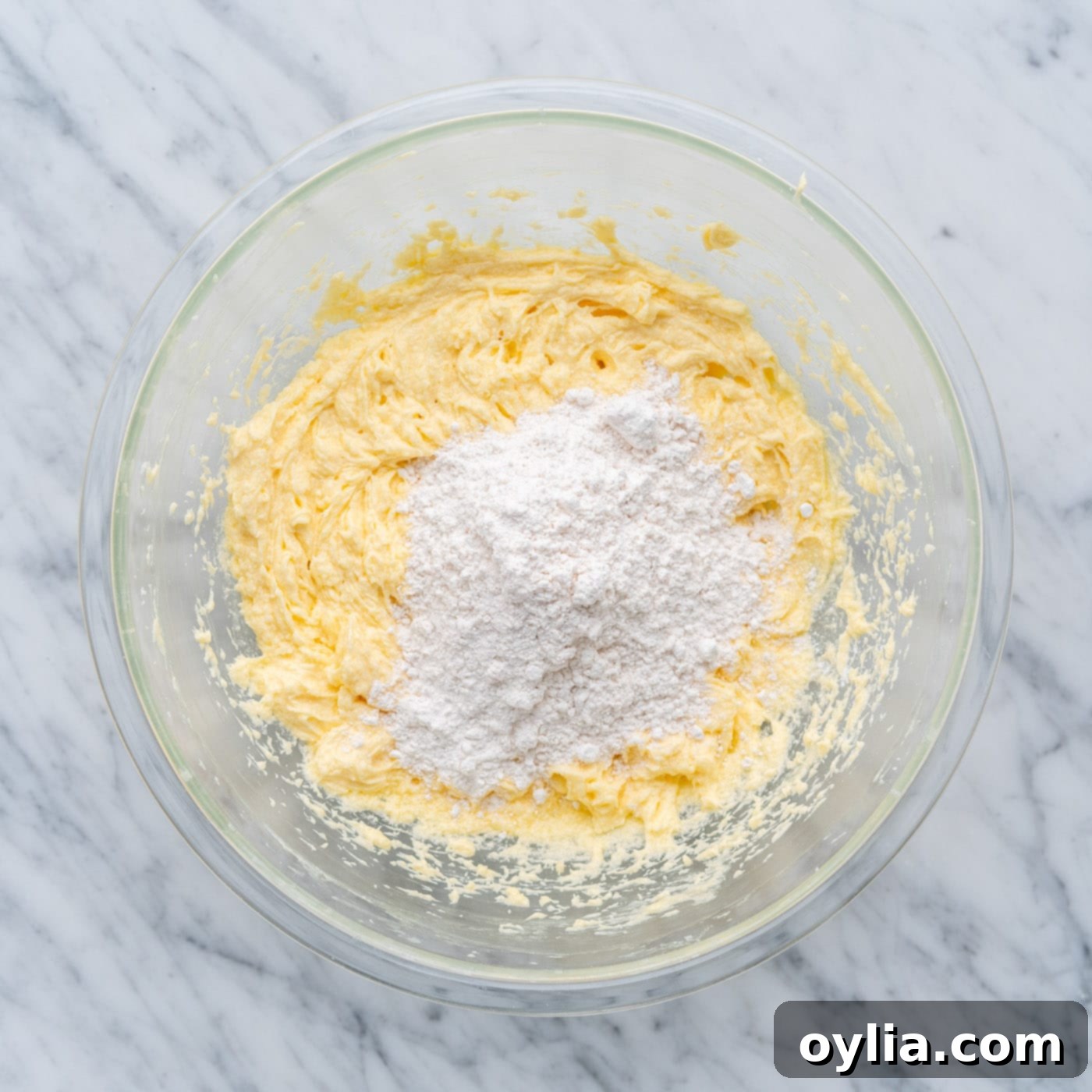 Dry ingredients being folded into the wet cake batter in a large bowl