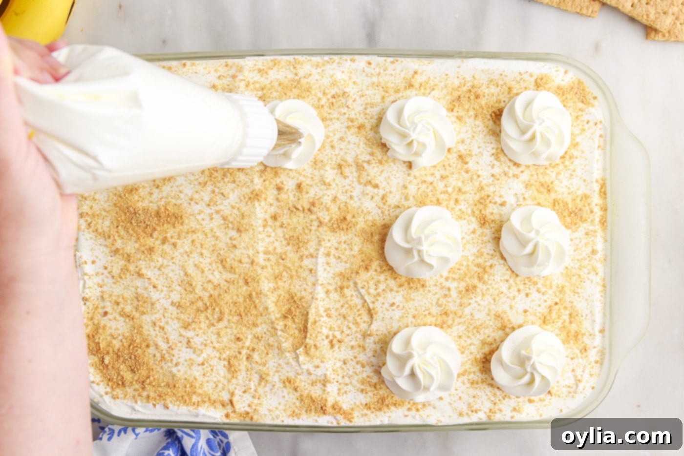 piping whipped cream on top of banana cream pie icebox cake