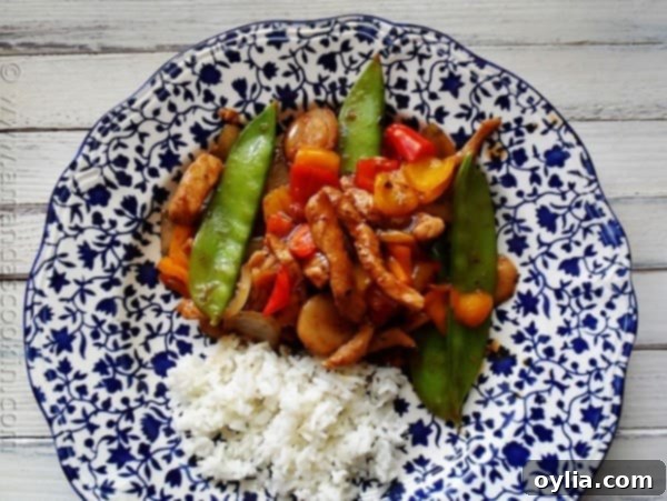 An overhead photo of a plate of peppered pork stir fry with sweet peppers with rice on the side.