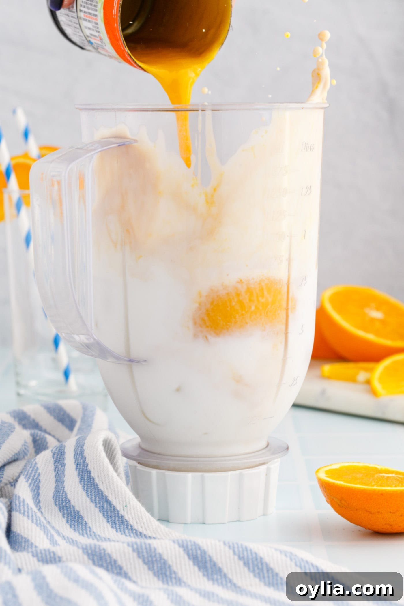 pouring orange julius ingredients into a blender