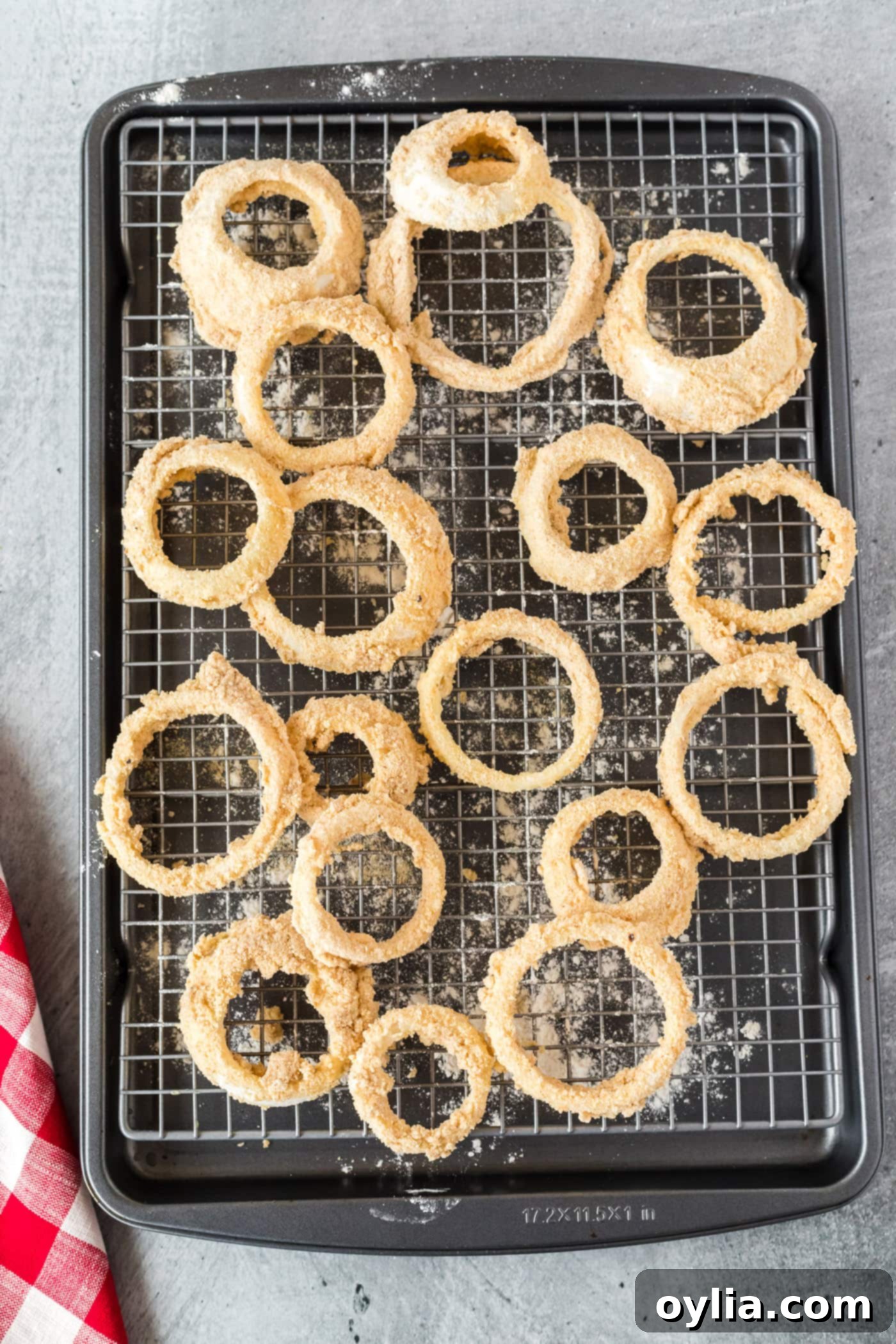 onion rings dipped in breadcrumbs on a baking sheet
